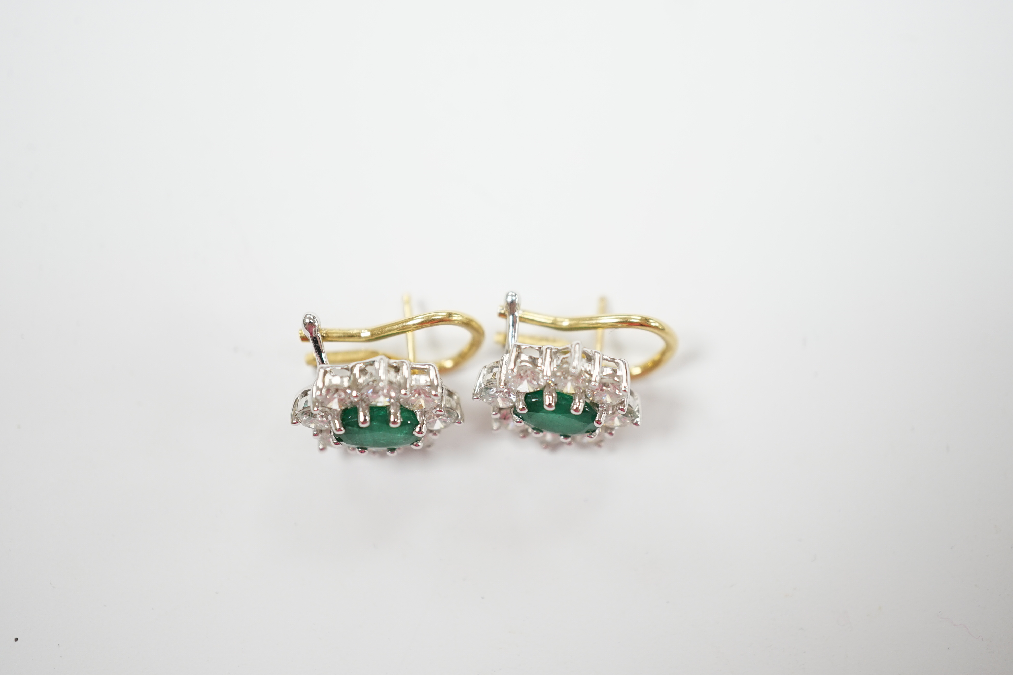 A modern pair of 18ct gold, emerald and diamond set oval cluster earrings, 13mm, gross weight 5.3 grams.